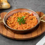Menemen borbulhante: ovos mexidos em tomate e pimentão, servidos em panela de barro; café da manhã tradicional em Cihangir.