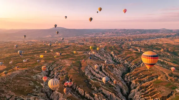 Vista aérea do Vale do Amor na Capadócia com dezenas de balões coloridos — viagem mágica pela Turquia.